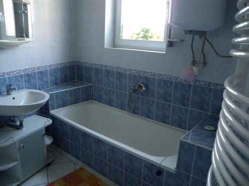 La salle de bains est pourvue de carrelage bleu, d'une baignoire et d'un lavabo. dans l'établissement Apartment Balatonkeresztur - Balaton 19286, à Balatonkeresztúr