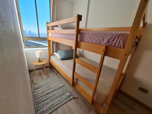 a bedroom with two bunk beds and a window at Loica Host - Departamentos amoblados a pasos del metro in Santiago