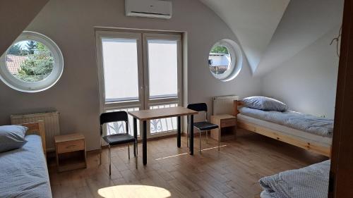 a room with a bed and a table and two windows at Hostel Centrum in Końskie