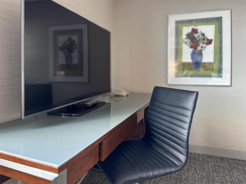 a desk with a black chair and a television at Coast Prince George Hotel by APA in Prince George