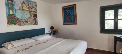 a bedroom with a bed and a painting on the wall at Il giardino di FraFa in Quartu SantʼElena