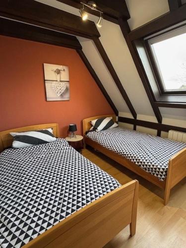 two beds in a room with two windows at Cottage des Cîmes in Climbach