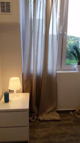 okno z zasłoną obok stołu i lampy w obiekcie Apartament Marina w mieście Sopot