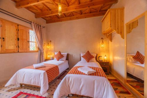 two beds in a room with wooden ceilings at Riad Berber Towers in Imlil
