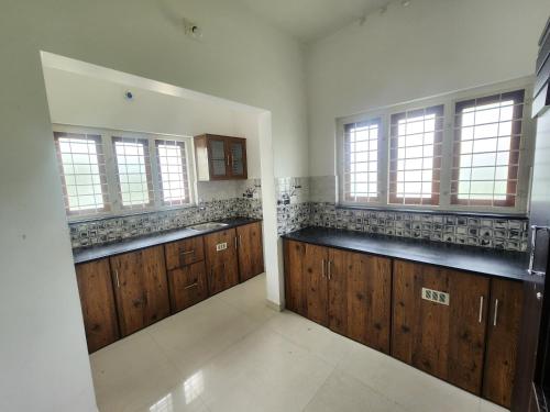 a large kitchen with wooden cabinets and windows at Happyhomes Homestay in Trivandrum