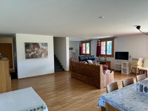 a living room with a couch and a television at PetitChevrier - 6BR Spacious Chalet in Villars - Designed for Accessibility in Ollon