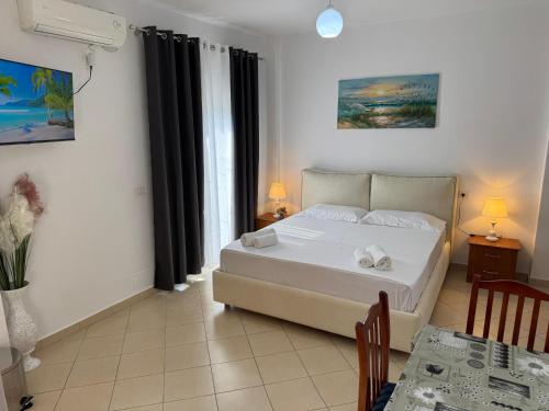 a bedroom with a large white bed and a table at Villa Dion in Ksamil