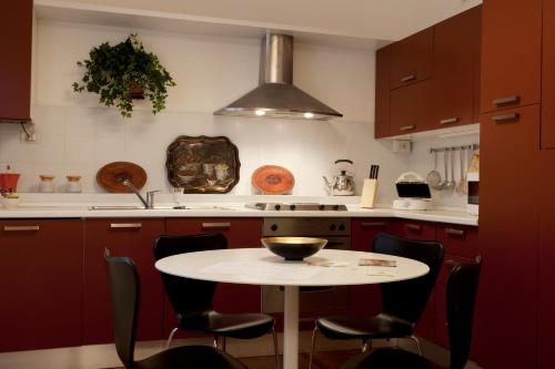 a kitchen with red cabinets and a white table and chairs at Exclusive Aparthotel La Reunion in Ravenna