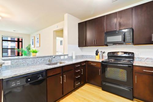 a kitchen with wooden cabinets and a stove and microwave at Comfort & Convenience in Trendy Crystal City Loft in Arlington