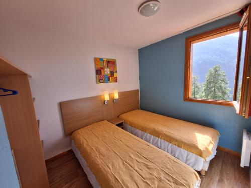 une chambre d'hôtel avec deux lits et une fenêtre dans l'établissement Bel appart au centre des Orres 1800 - Grand balcon Belle vue - A côté pistes, aux Orres