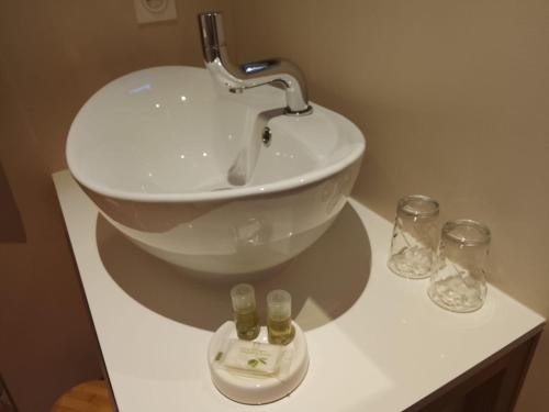 a bathroom with a sink and two glasses on a counter at Chambres d'Hôtes Le Mimosa in Saint-Saturnin-de-Lucian