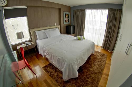 a bedroom with a large white bed and a window at Arvo Hotel Boutique in Trujillo
