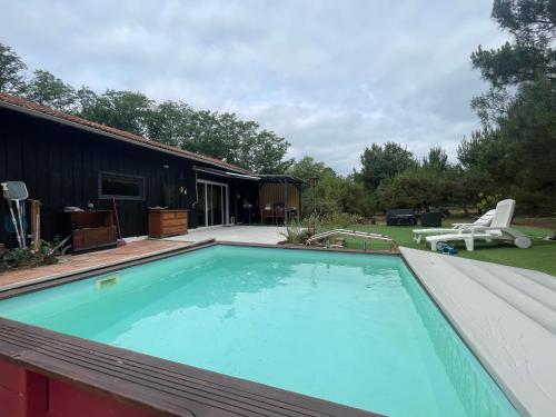 - une grande piscine dans une cour à côté d'une maison dans l'établissement La grange sous les pins landais, à Pissos