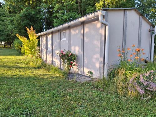 biała szopa z kwiatami na podwórku w obiekcie Gîte Nature et détente w mieście Aubréville