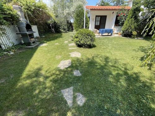 a yard with rocks in the grass with a house at La Casuța - 500sqm garden theseaside in Mamaia Nord