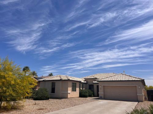 a house with a garage and a cloudy sky at Goodyear Cul-De-Sac Master Bedroom in Goodyear