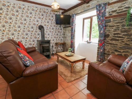 a living room with two leather couches and a wood stove at The Stable in Llandysul