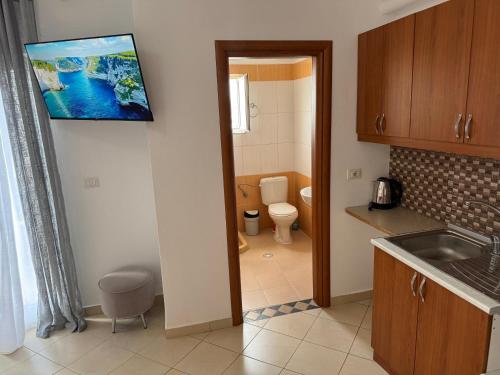 a kitchen with a sink and a toilet and a tv on the wall at Villa Dion in Ksamil