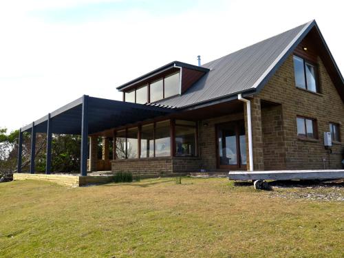 a brick house with a metal roof on a field at Cloudy Bay Villa in South Bruny