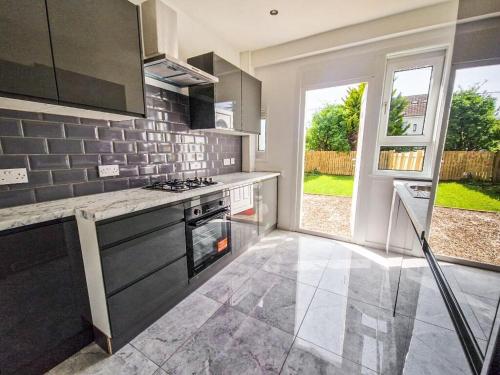 a kitchen with a stove top oven next to a window at Modern and stylish 3 bedroom 2 bathroom west end house with Free WiFi and parking in Scotstoun West Station