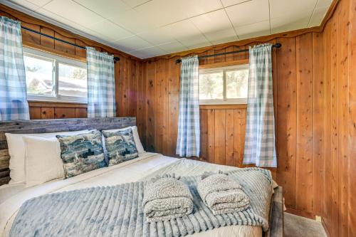 a bed in a room with wooden walls and windows at Dog Friendly Cabin with Yard and Mtn Views in Cascade in Cascade-Chipita Park