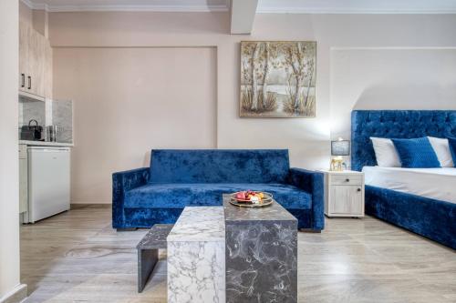 a living room with a blue couch and a bed at Valery Apartments in Pefkohori