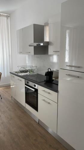 une cuisine avec des armoires blanches et un four à plaques de cuisson dans l'établissement Spacieux 2 pieces a Marseille 1er, à Marseille