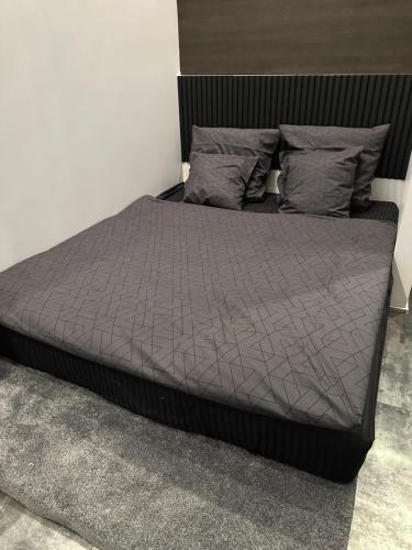 a bed with a gray comforter and pillows at B&M Jacuzzi Rezidencija SELF CHECK - IN in Vilnius