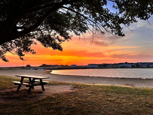 - une table de pique-nique assise sur la plage près de l'eau dans l'établissement Maison familiale design proche plage draps fournis, à Étel