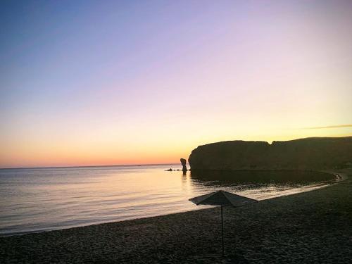 a person standing on a beach with an umbrella at Vrisaki 81400, Lemnos Island in Mirina