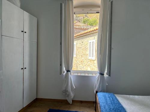 a bedroom with a window and a bed with a blue rug at Vrisaki 81400, Lemnos Island in Mirina