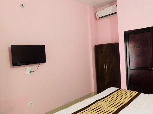 Chandigarh AirportMahadev Homestay !! Preferred Partner ! Walking Distance To Chandigarh Int'l Airport !的卧室配有一张床和壁挂式平面电视。