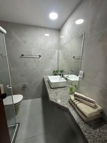 a bathroom with a sink and a toilet and a mirror at Residencial Pasárgada, apto 602 in Vila Velha