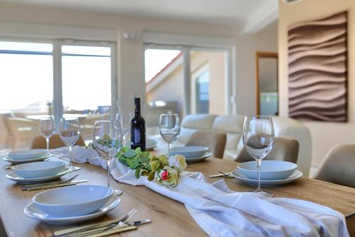 a table with glasses and plates and a bottle of wine at Penthouse Sophia in Medulin