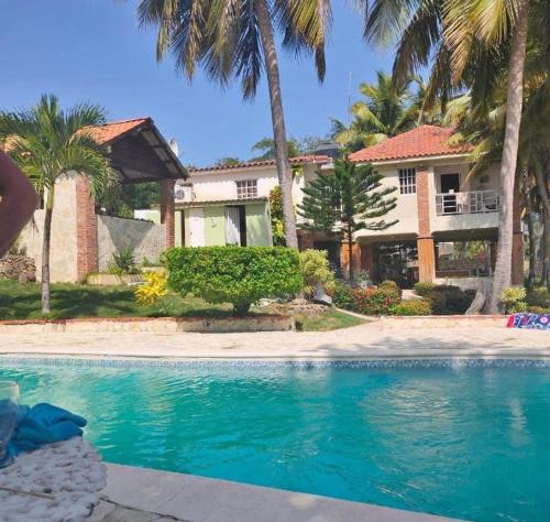 ein Swimmingpool vor einem Haus mit Palmen in der Unterkunft Emmanuel villas luxury in Puerto Plata