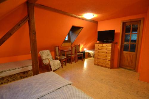 a bedroom with an orange room with a bed and a desk at Penzion Brtníky 23 in Brtníky