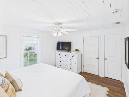 a white bedroom with a bed and a ceiling fan at Coastal Cottage in Port Saint Joe
