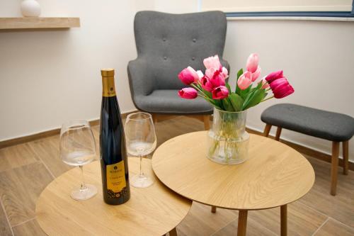 a table with a vase of pink flowers and a bottle of wine at Blisséa in Piraeus