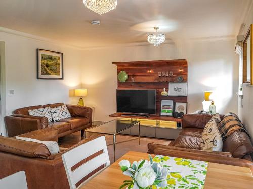 a living room with leather couches and a television at Torrance At Abbey Park Avenue in St. Andrews