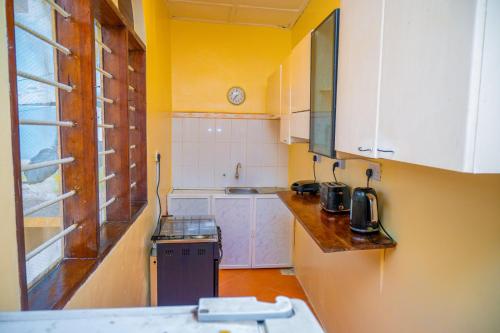una pequeña cocina con paredes amarillas y armarios blancos. en Malkiya house, en Zanzíbar