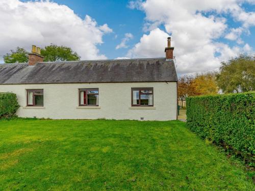 a white house with a hedge in front of it at 3 Bed in Blairgowrie 90111 in Blairgowrie