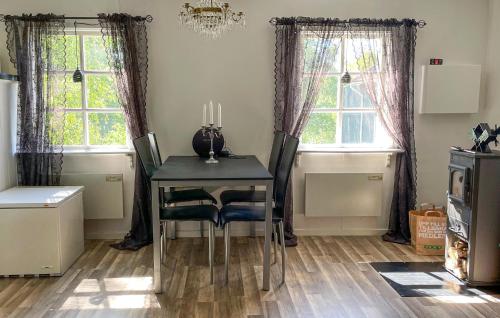 a dining room with a table and two windows at 1 Bedroom Lovely Home In Äspered in Äspered