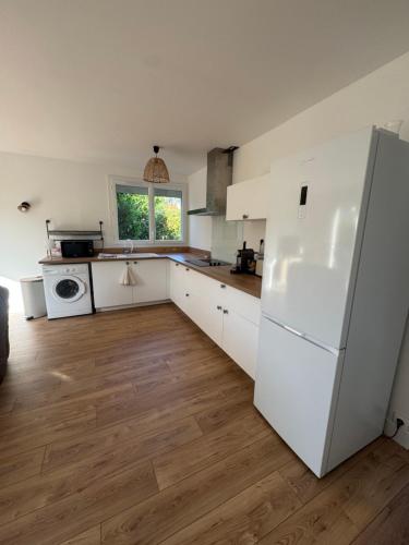 Il comprend une cuisine équipée d'appareils électroménagers blancs et d'un réfrigérateur blanc. dans l'établissement Maison Le Verger de Manou, à Saint-Palais-sur-Mer