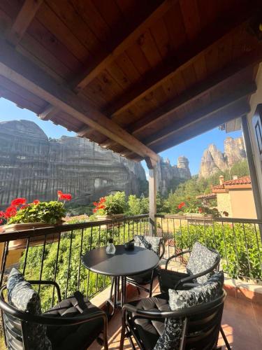 a balcony with a table and chairs with a view of the mountains at Halasma Meteora in Kastrákion