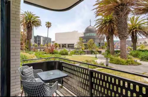 a balcony with chairs and a table and palm trees at KML Nine Palms luxury 101 in Cape Town