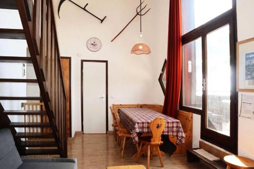 une salle à manger avec une table, des chaises et une horloge murale dans l'établissement Résidence Le Cairn - COEUR STATION LES ORRES - Résidence LE CAIRN - Triplex 12 Personnes MAE-6391, aux Orres