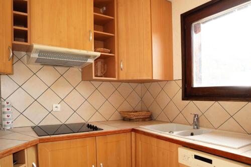 une cuisine avec des armoires en bois, un évier et une fenêtre dans l'établissement Résidence Le Cairn - COEUR STATION LES ORRES - Résidence LE CAIRN - Triplex 12 Personnes MAE-6391, aux Orres