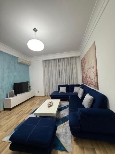 a living room with blue couches and a tv at Peaky Hotel in Durrës