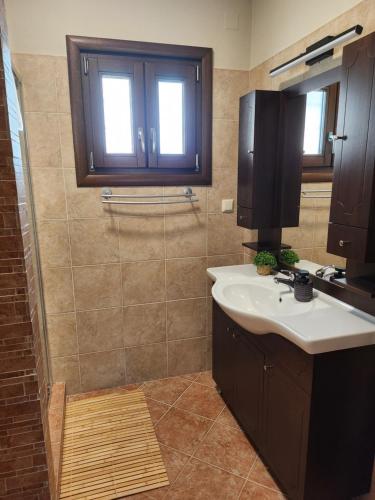a bathroom with a sink and a window and a shower at Halasma Meteora in Kastrákion