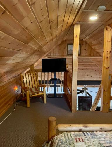 a living room with a wooden ceiling and a tv at The Elms Waterfront Cottages in Lake Luzerne